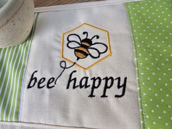 Tassenuntersetzer in Patchworkarbeit, bestickt mit einer Biene und "bee happy". 15 x 30 cm Größe, Mitbringsel und Geschenkidee für Honigliebhaber