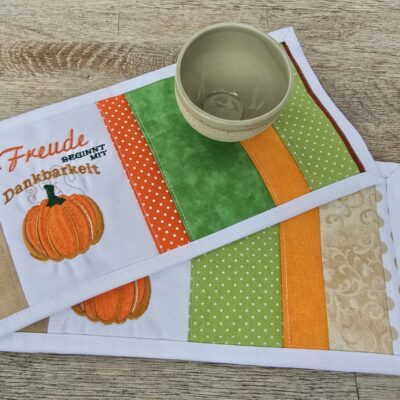 Tassenuntersetzer in Patchworkarbeit, bestickt mit Kürbis zur Herbstzeit. Mitbringsel und Geschenkidee zur herbstlichen Tischdekoration